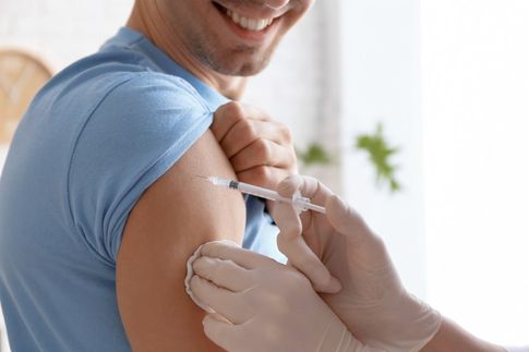 Sairaanhoitaja antaa miehelle rokotuksen